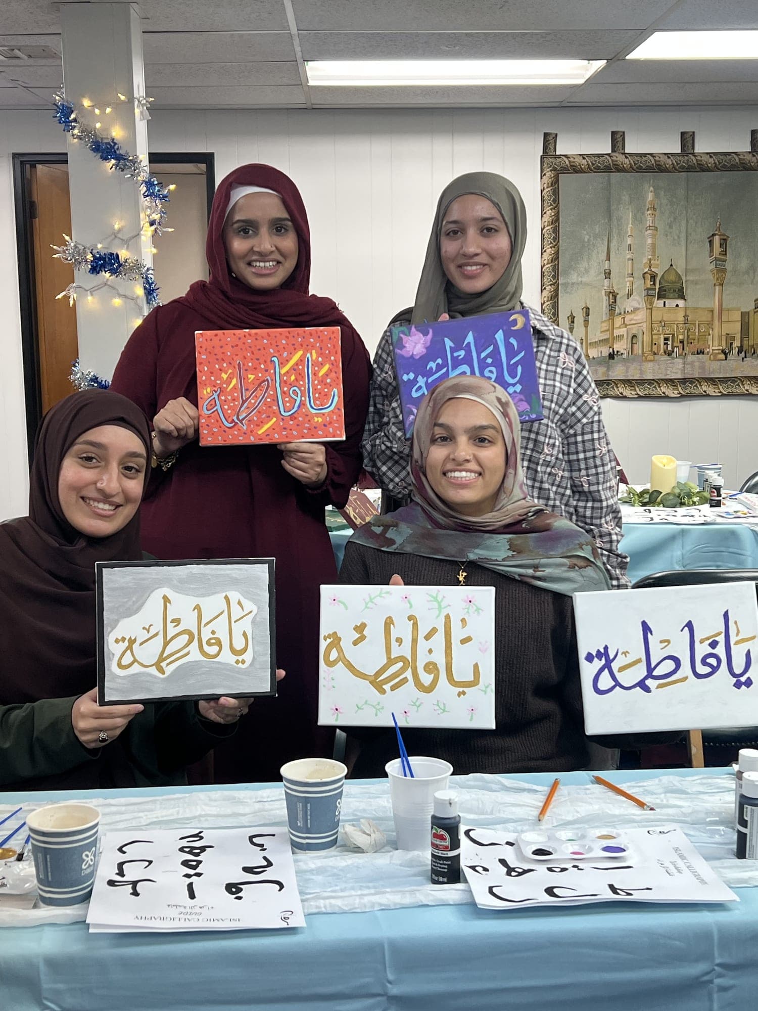 Participants holding their Arabic calligraphy artwork at a community workshop